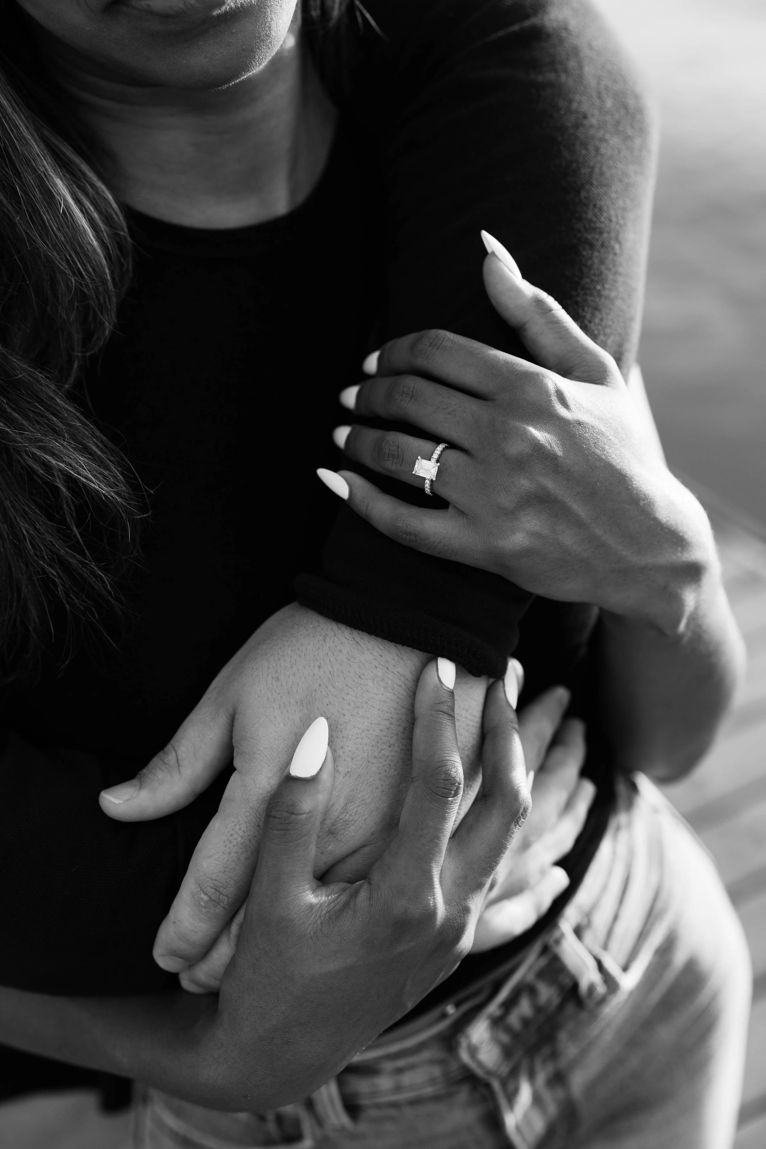 Close-up of several hands, some with rings and manicured nails, holding onto each other in a group gesture.