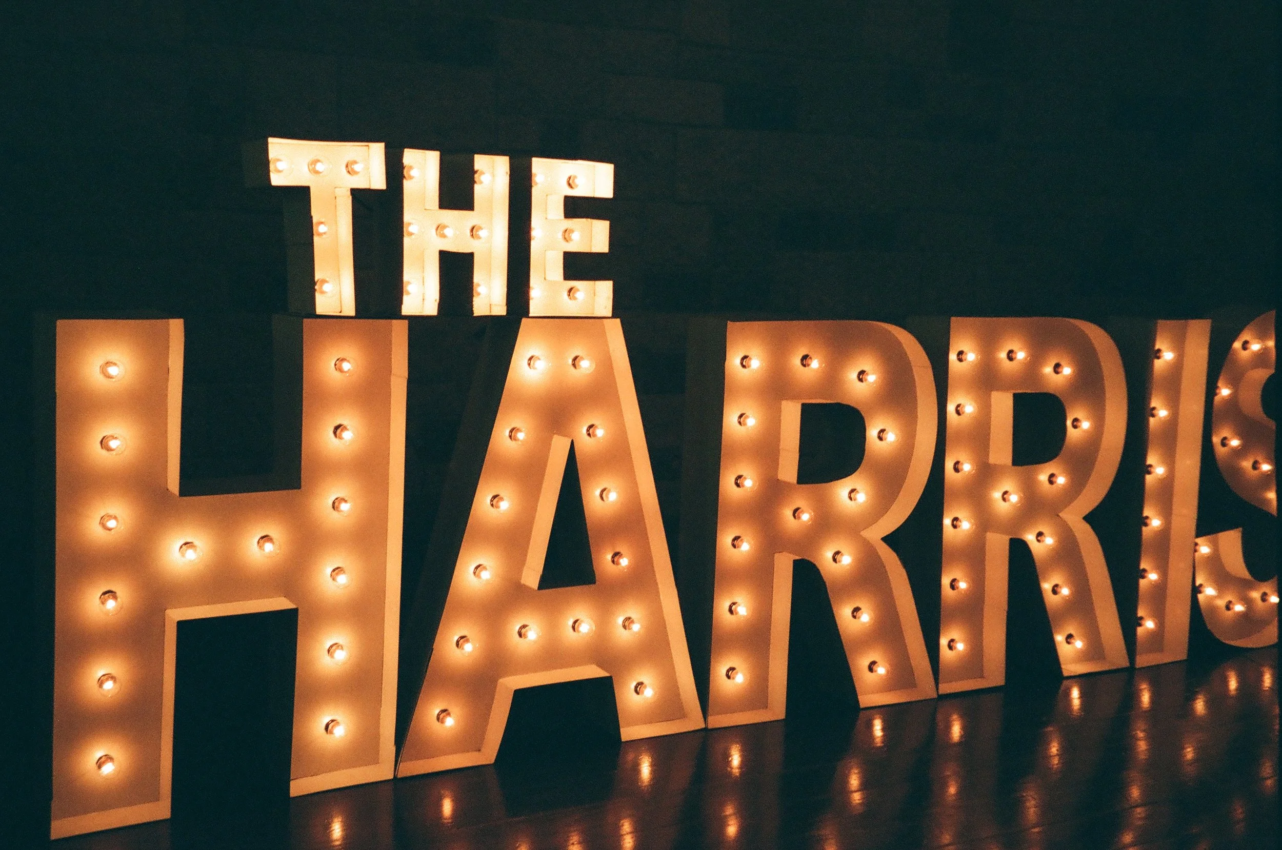Light-up marquee sign spelling 'THE HARRIS' with warm white lights against a dark background.