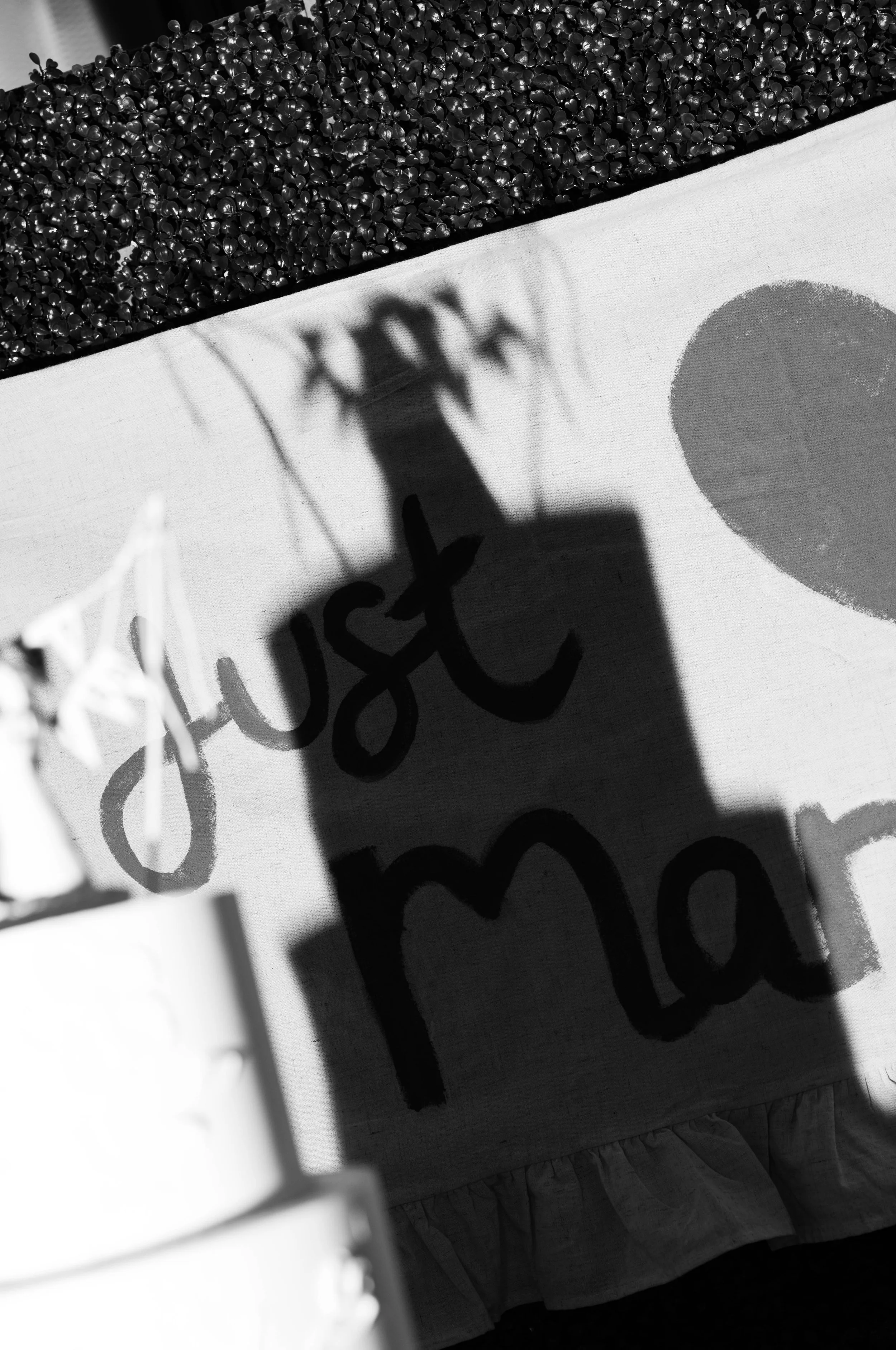 Shadow of a child holding a basketball, cast onto a piece of paper with handwritten text and a drawing of a heart, while standing outside near a hedge.