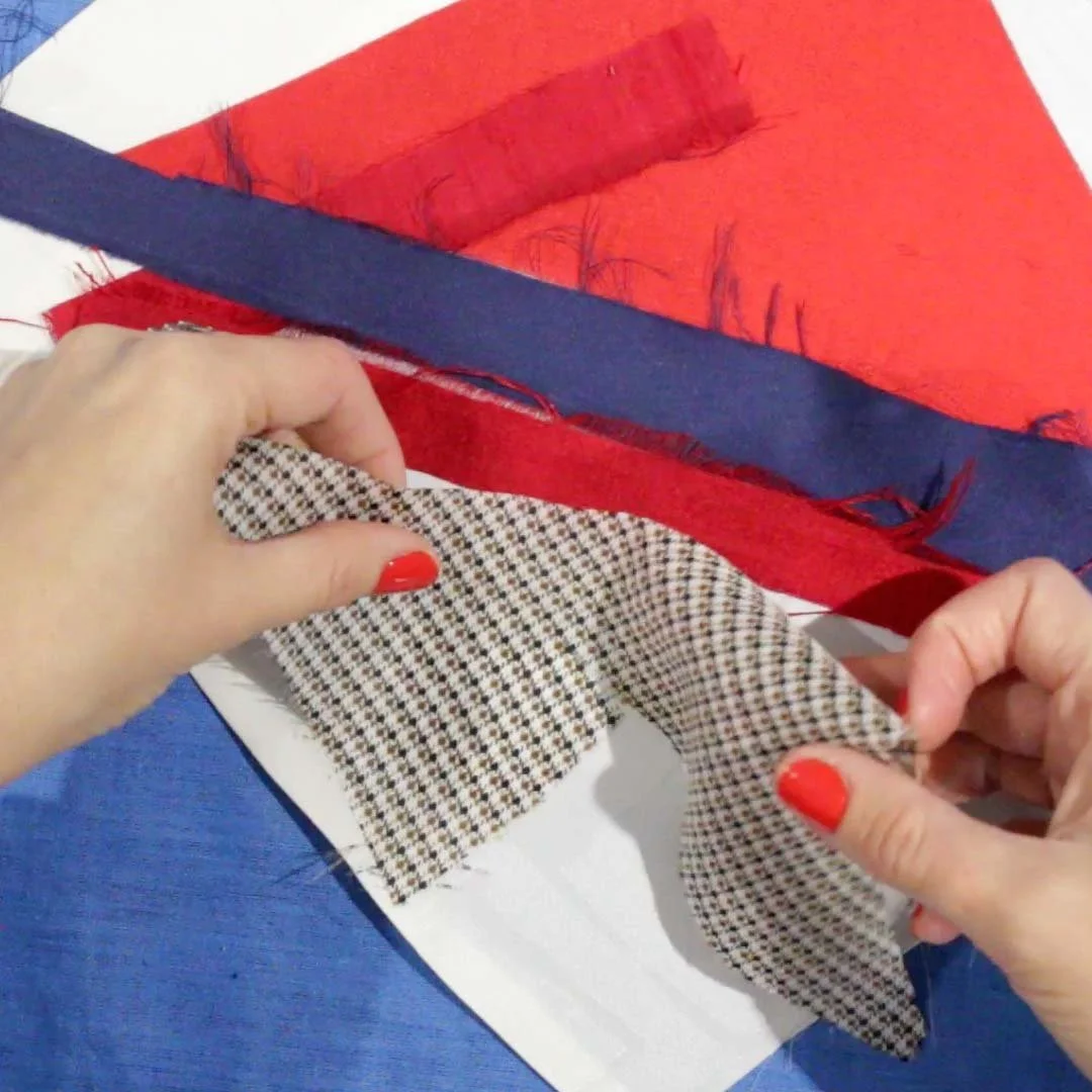 Person assembling an eclectic mix of scrap fabric to be sewn together with an improvised patchwork technique