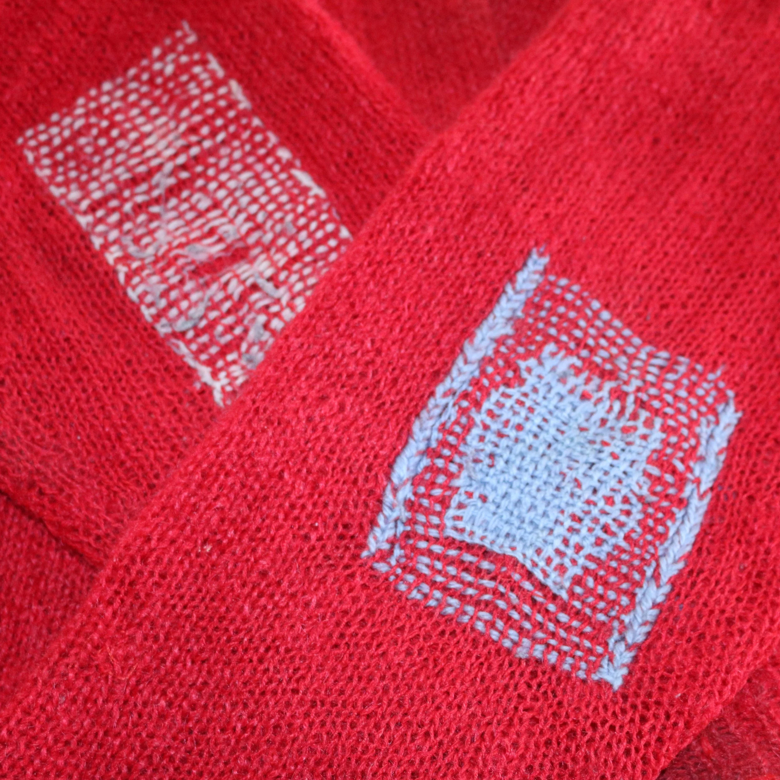 Close-up of red knit with patches of darning repair