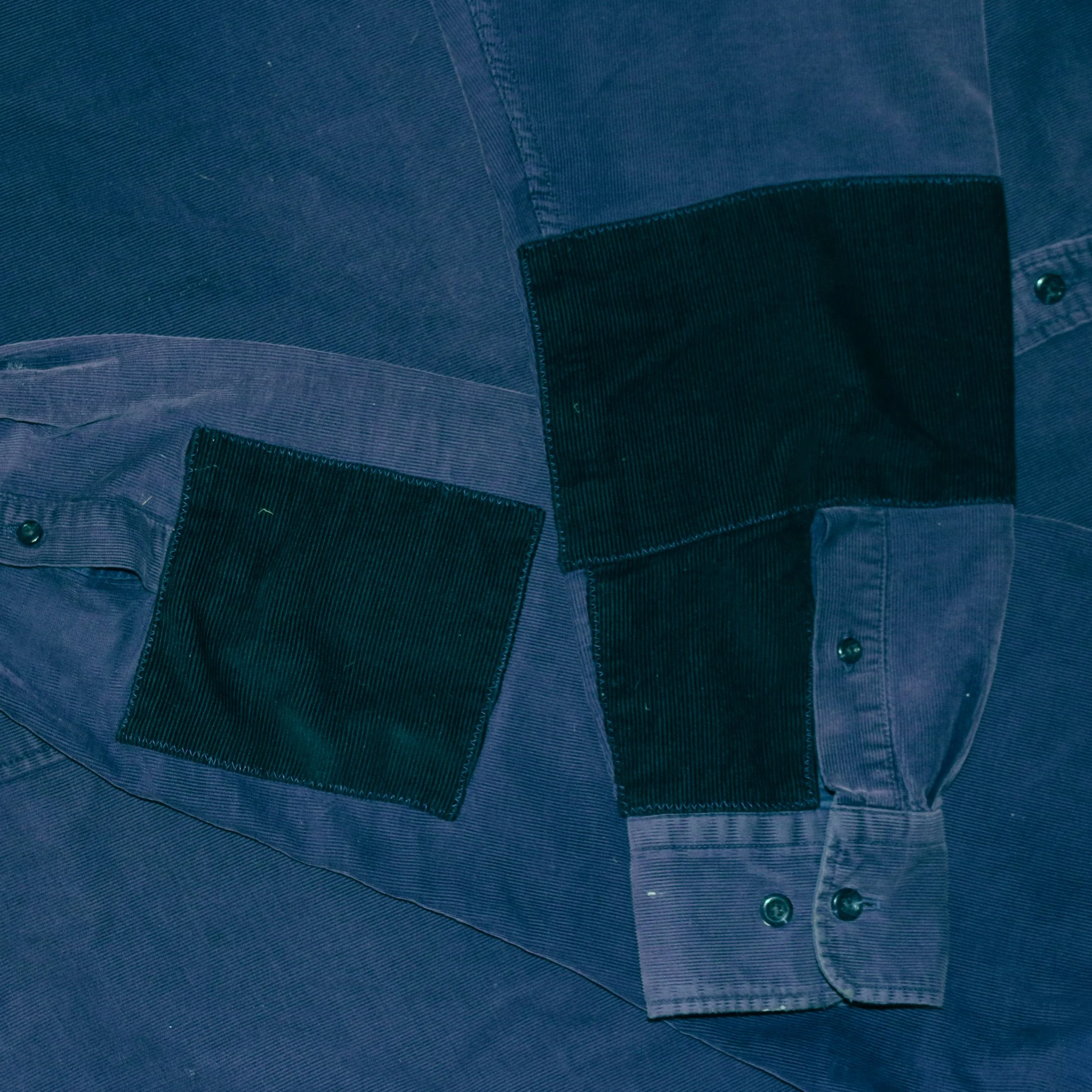Close-up view of a corduroy shirt that has ben mended with patches to repair tears in the elbows