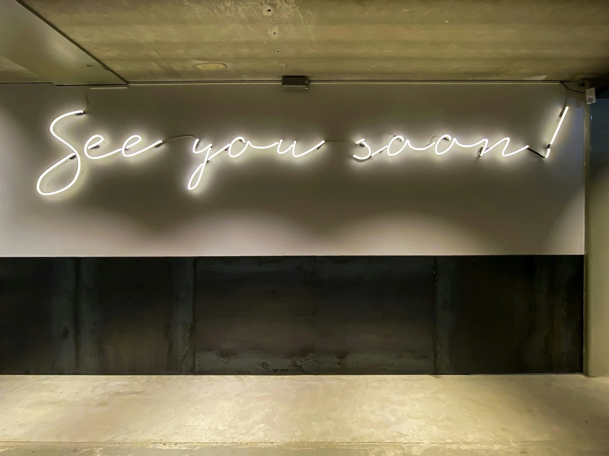 Neon sign on wall that reads 'See you soon!'