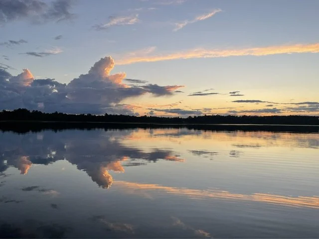Calm lake reflecting a partly cloudy sky during sunset