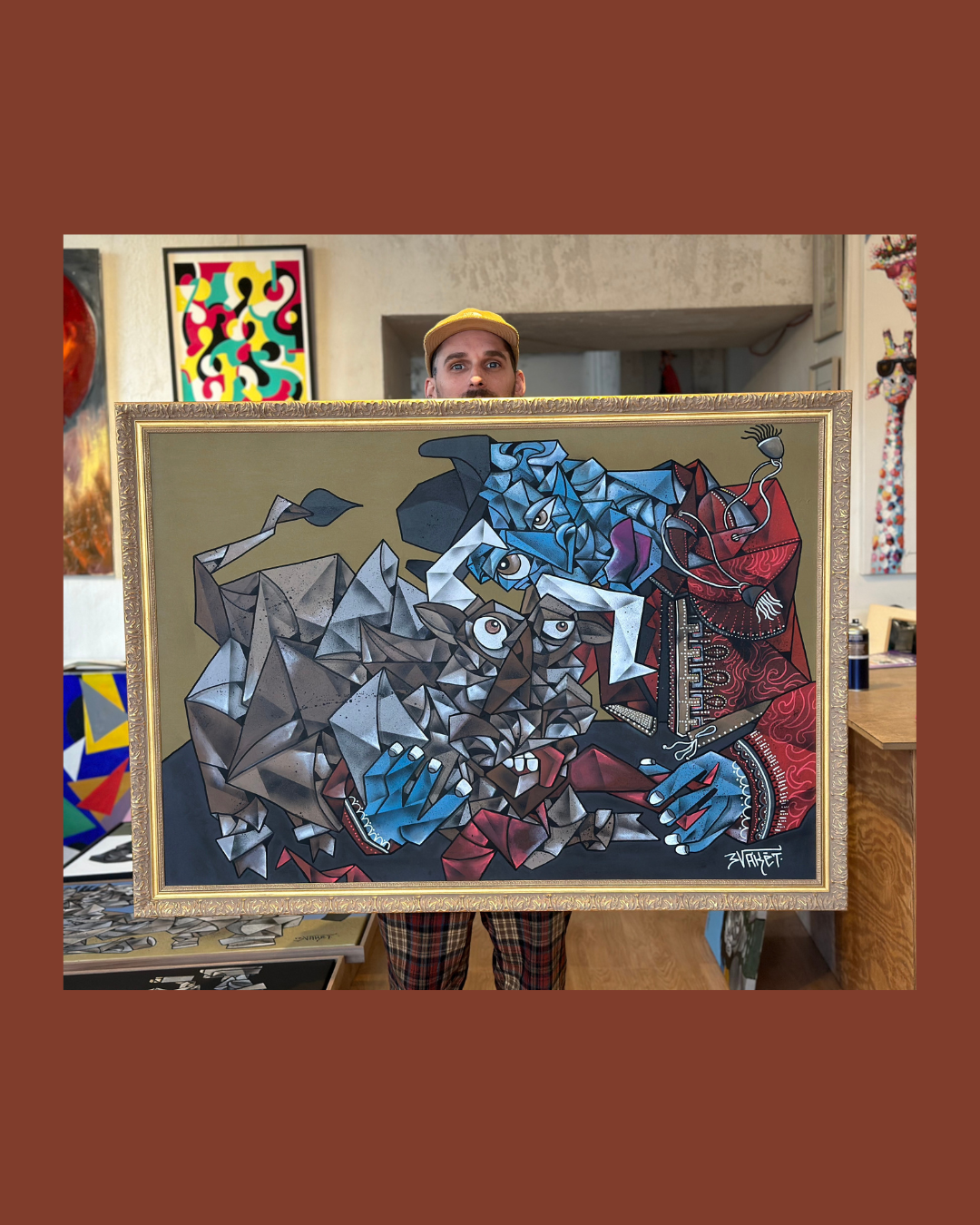 Un homme tenant une peinture abstraite représentant un taureau et un homme avec un pinceau dans un musée ou une galerie d'art.