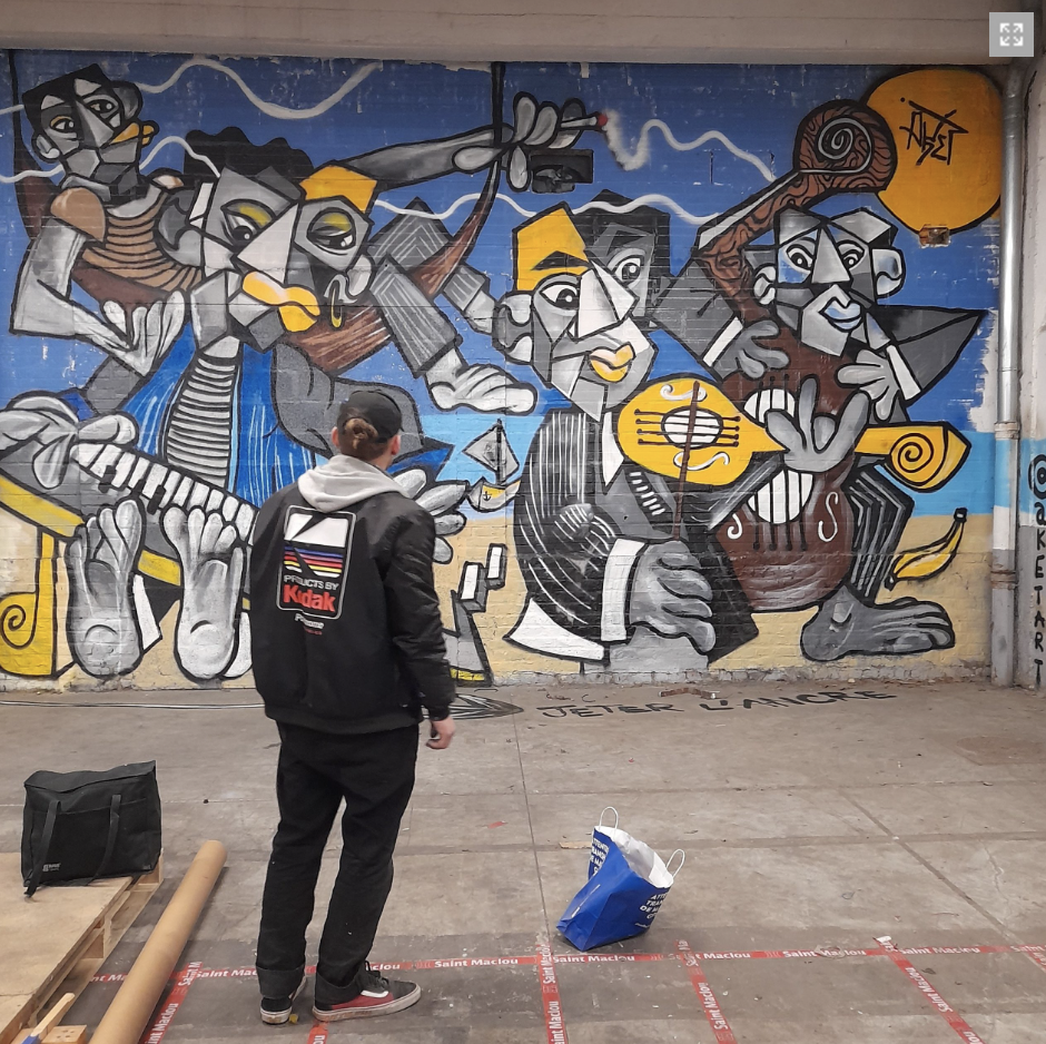 Un garçon regarde un mur de graffiti représentant six musiciens stylisés jouant de différents instruments, avec un fond bleu et des éléments jaunes et noirs.