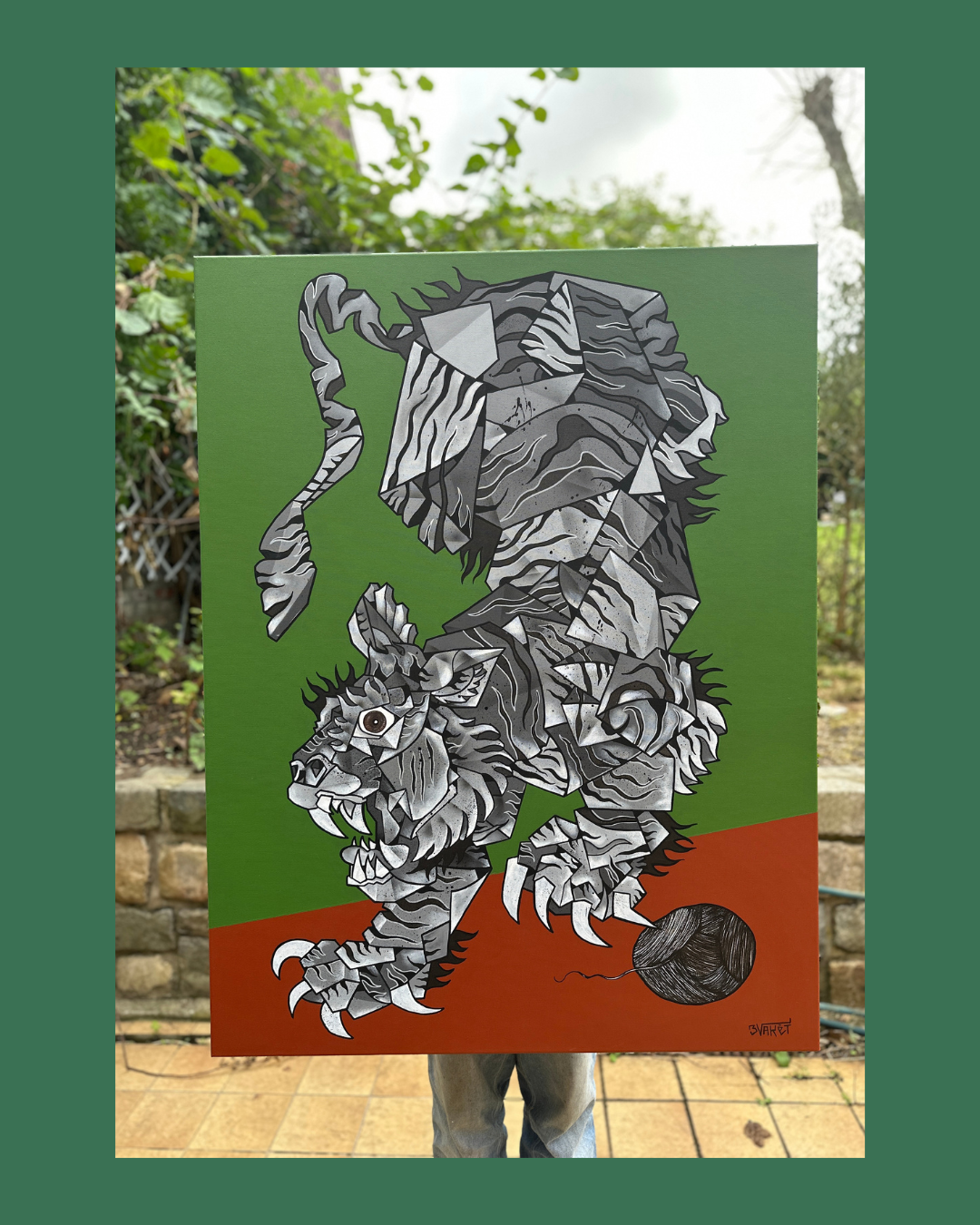 Une peinture représentant un lion dans un style géométrique noir, blanc et gris sur un fond vert, avec balle de laine noire sous sa patte.