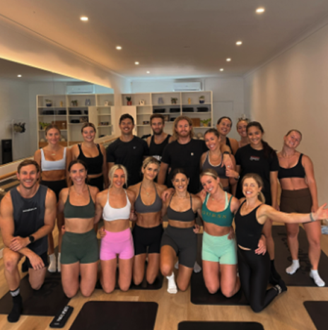 Group of people in workout attire posing in a fitness studio.