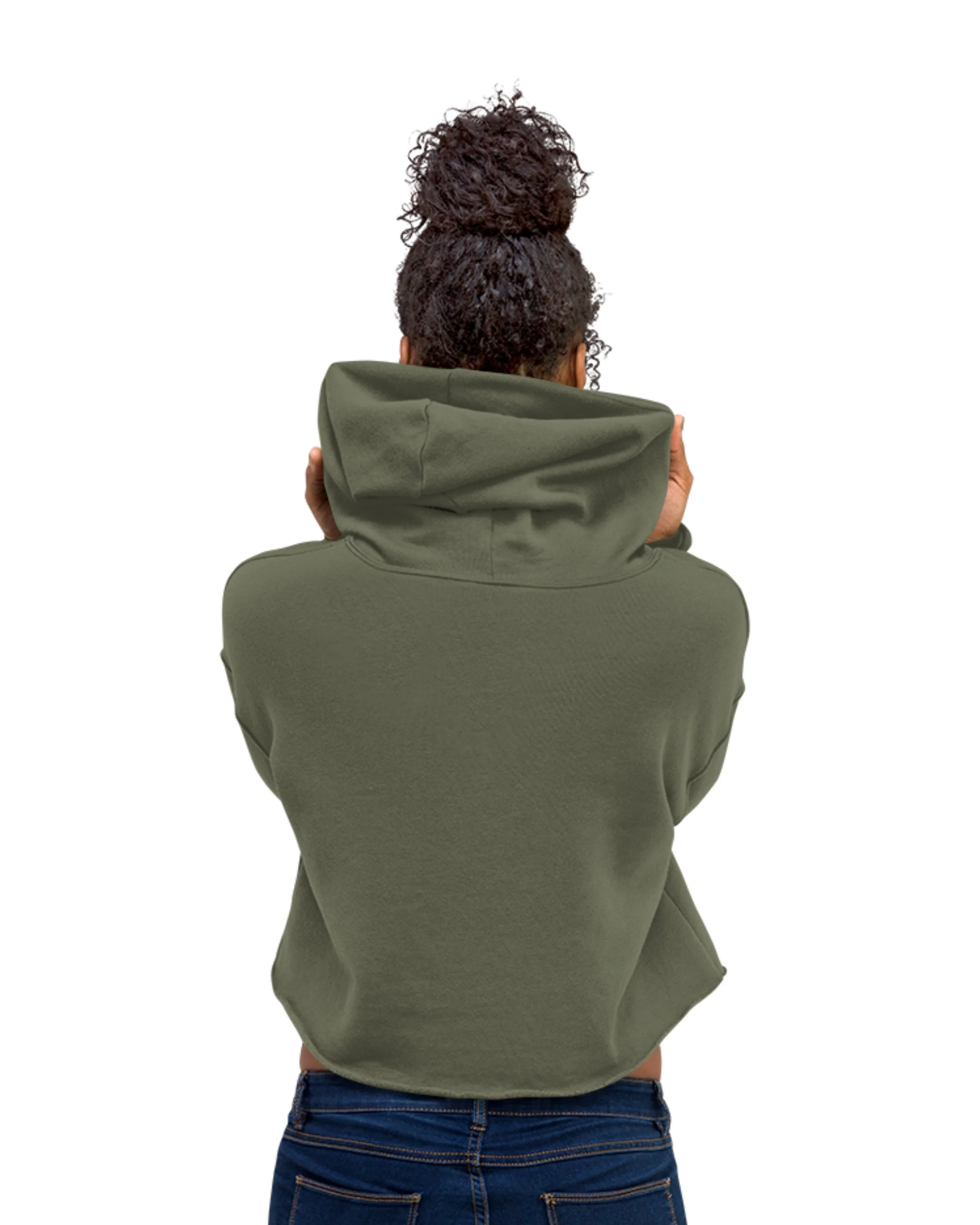 Back of a person with curly hair in a large bun, wearing a green hoodie and blue jeans, holding the hoodie with both hands, facing away from the camera, against a white background.
