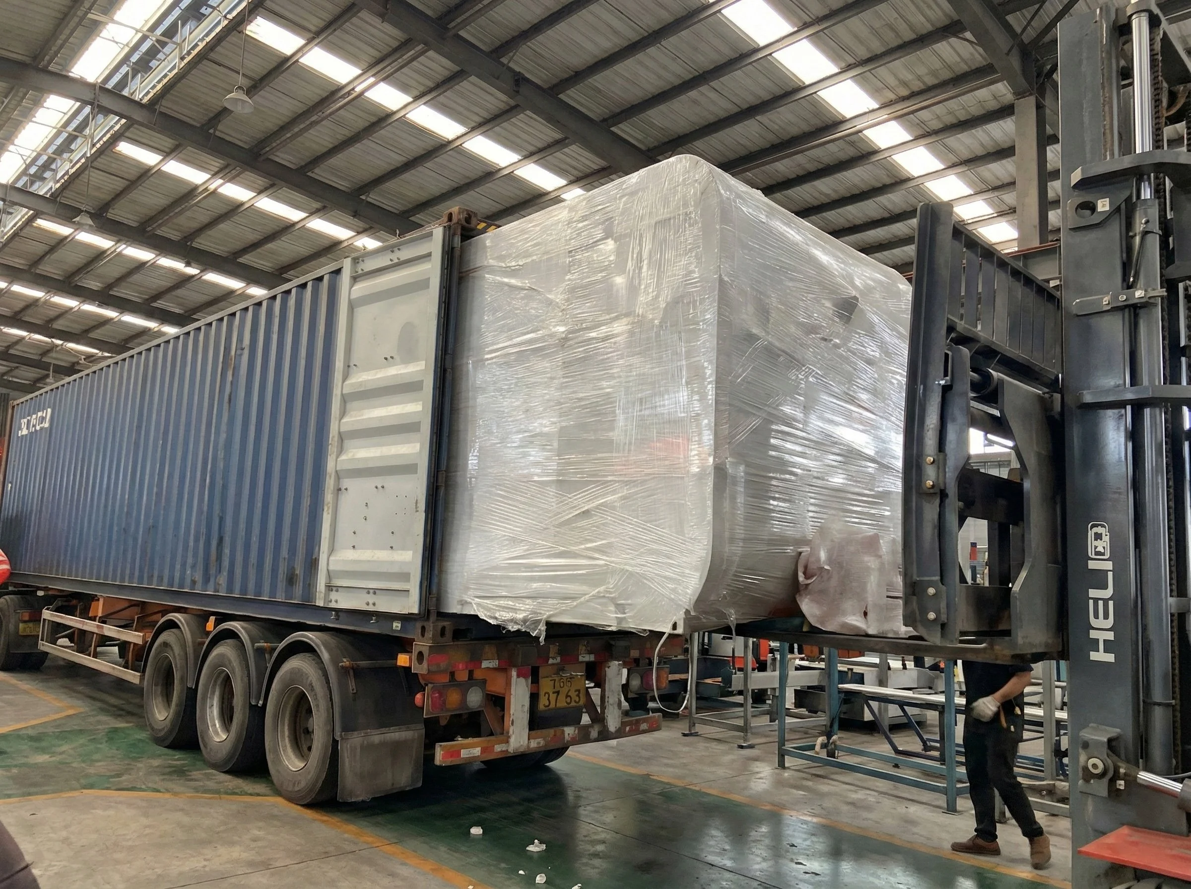 A large shipping container on a truck, with wrapped and protected item or equipment inside a warehouse.