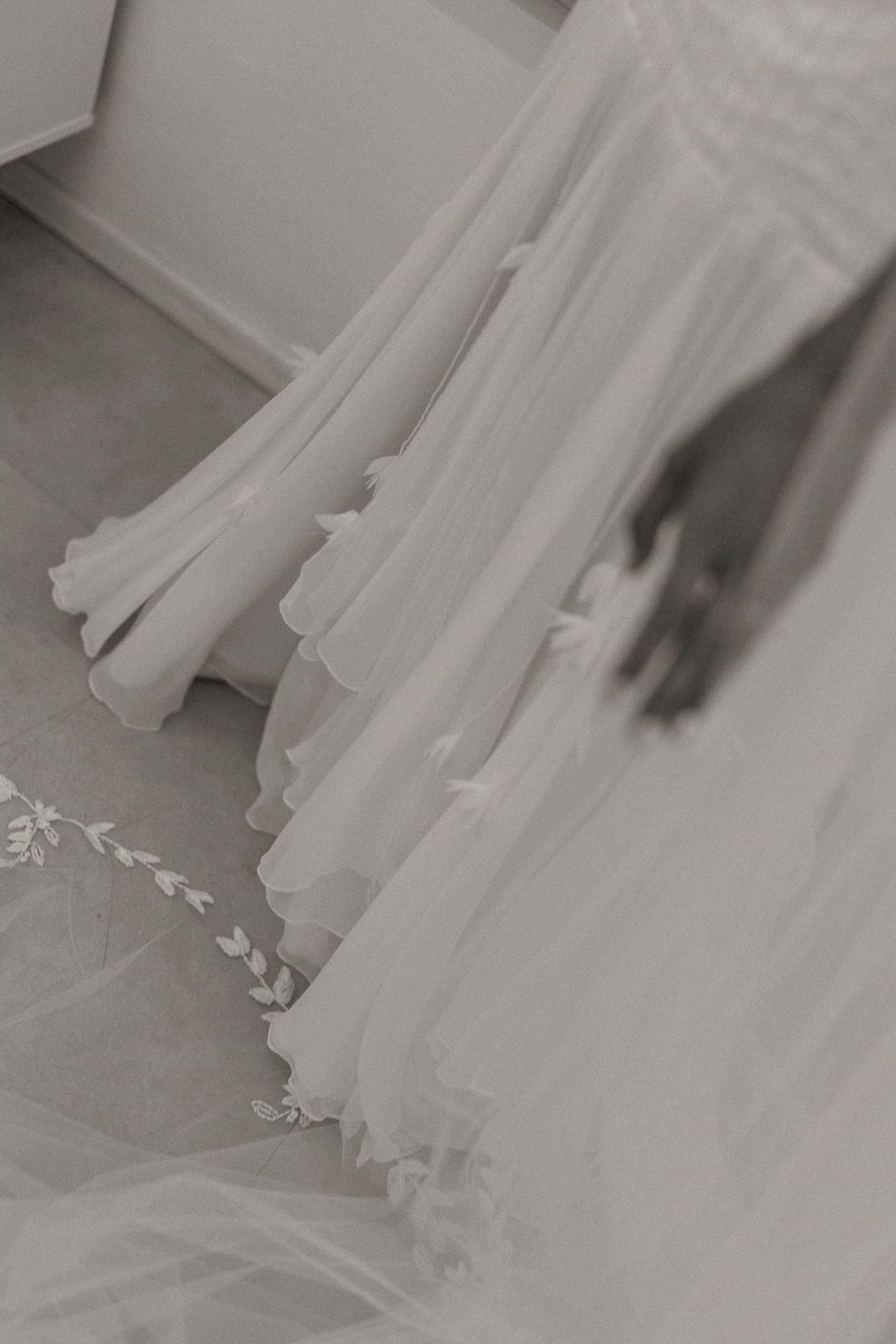 Vários vestidos de noiva brancos pendurados em cabides com uma saia de tule na frente.