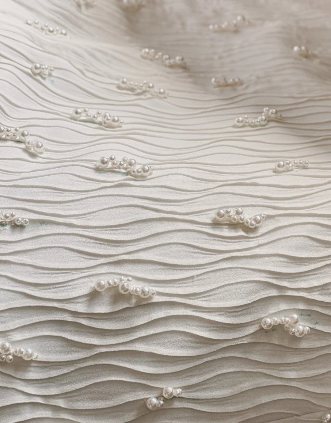 Texto em relevo branco com pontos de pérolas distribuídos em padrão ondulado.