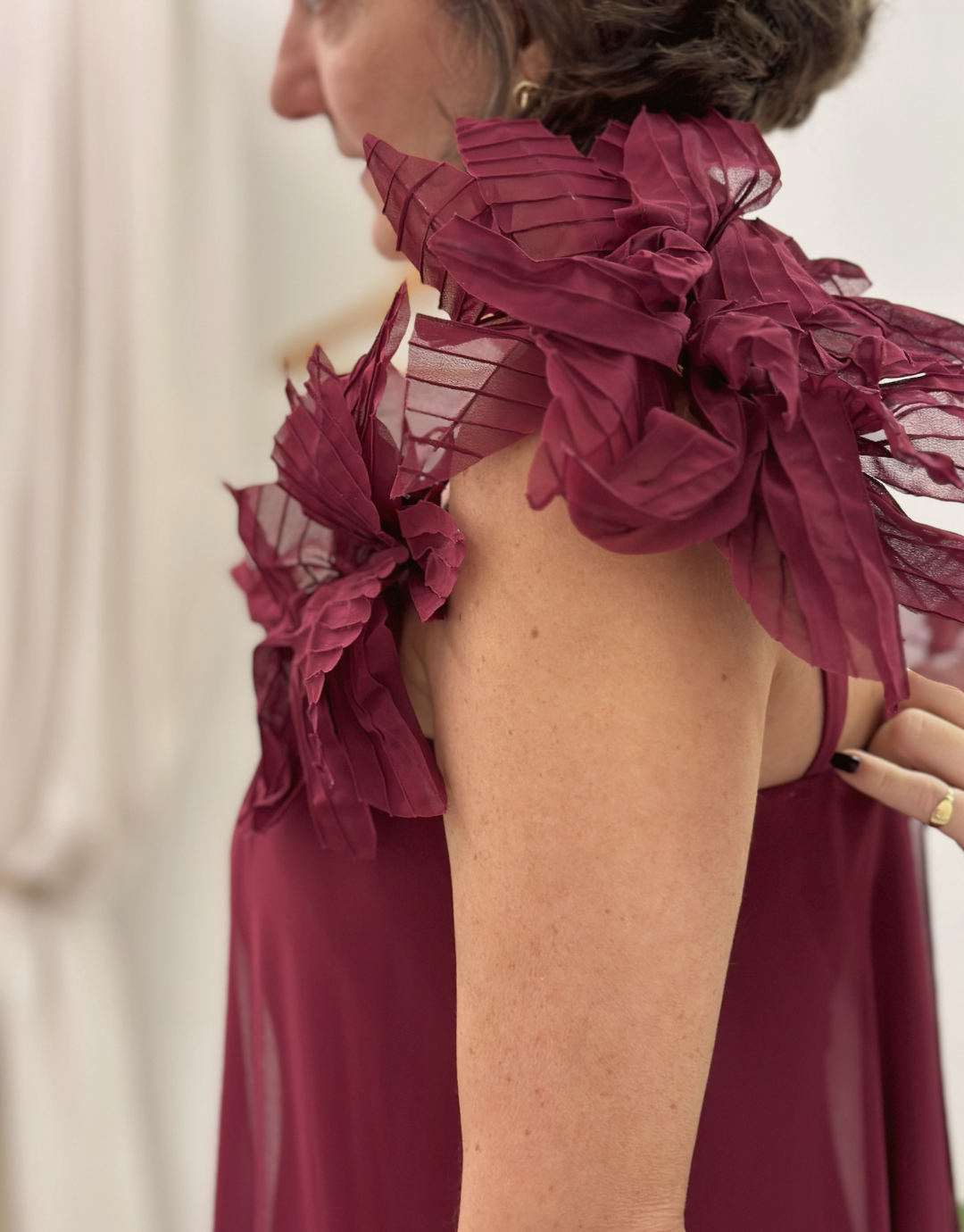 Mulher vestindo vestido vermelho com detalhes em folha de seda na abordagem do ombro.