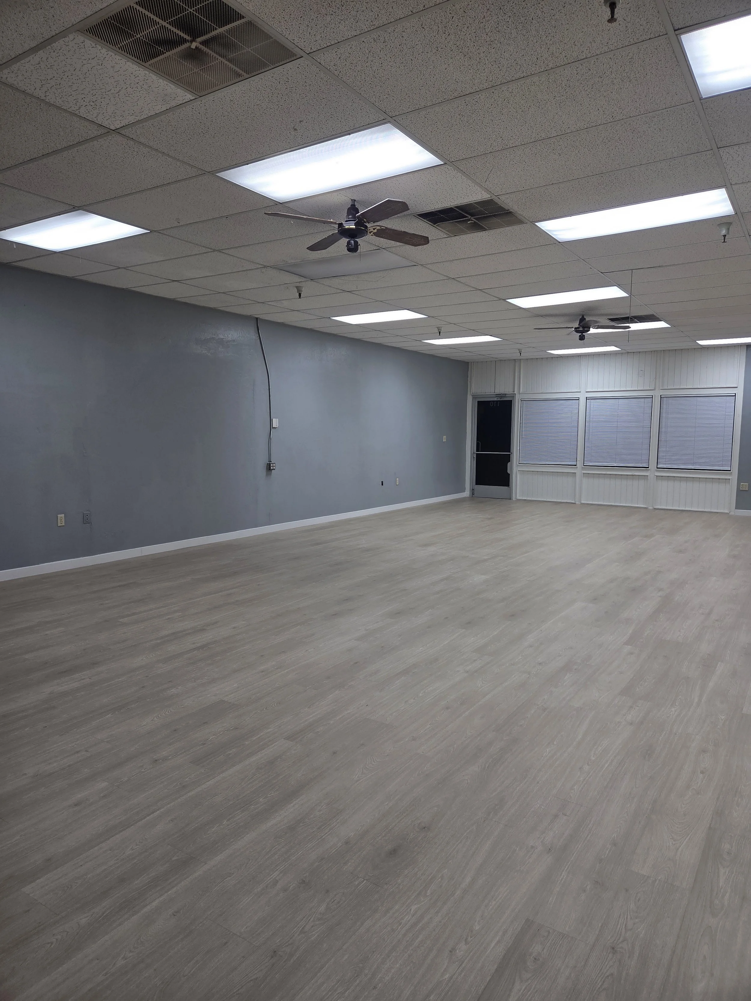 View of the dance studio back wall with gray walls and open light flooring, creating a clean and spacious environment