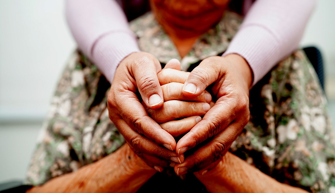 Multiple hands, aged and young, gently holding each other in a circle, symbolizing care and support.