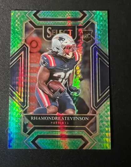 Football trading card of Rhamondre Stevenson in Patriots uniform holding a football.
