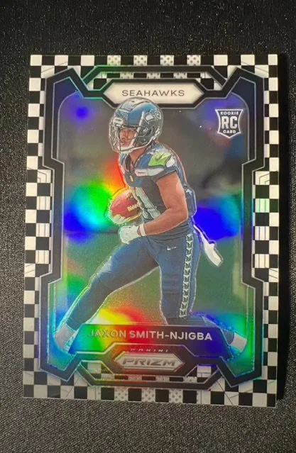 Holographic Seattle Seahawks rookie trading card featuring a football player holding a ball, with rainbow reflections, checkered border, and text indicating player Axton Smith.