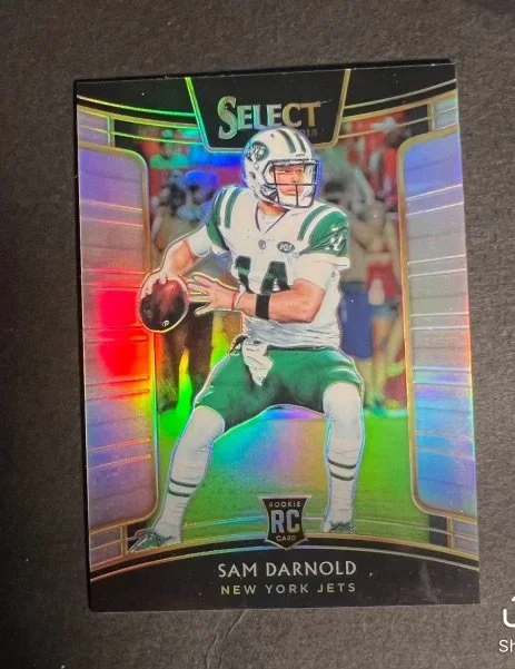 Sports trading card of Sam Darnold, a rookie quarterback for the New York Jets, with a rainbow holographic background.