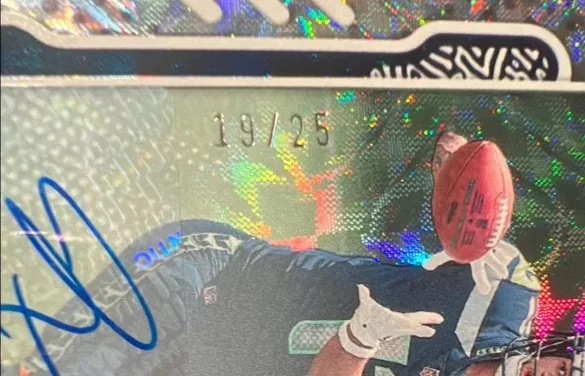 A close-up of a limited edition trading card featuring a football player holding a football. The card shows the number 19/25, indicating it is the 19th card out of 25. The card has holographic shiny patterns with the Panini and NFL logos.