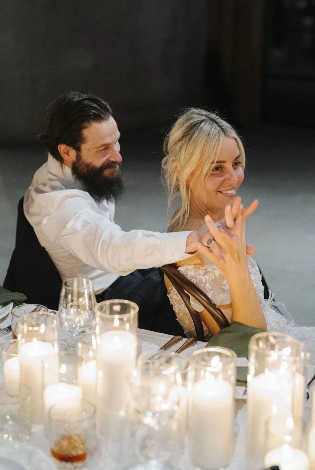 A couple dancing at a wedding reception, with candles on the table in the foreground.
