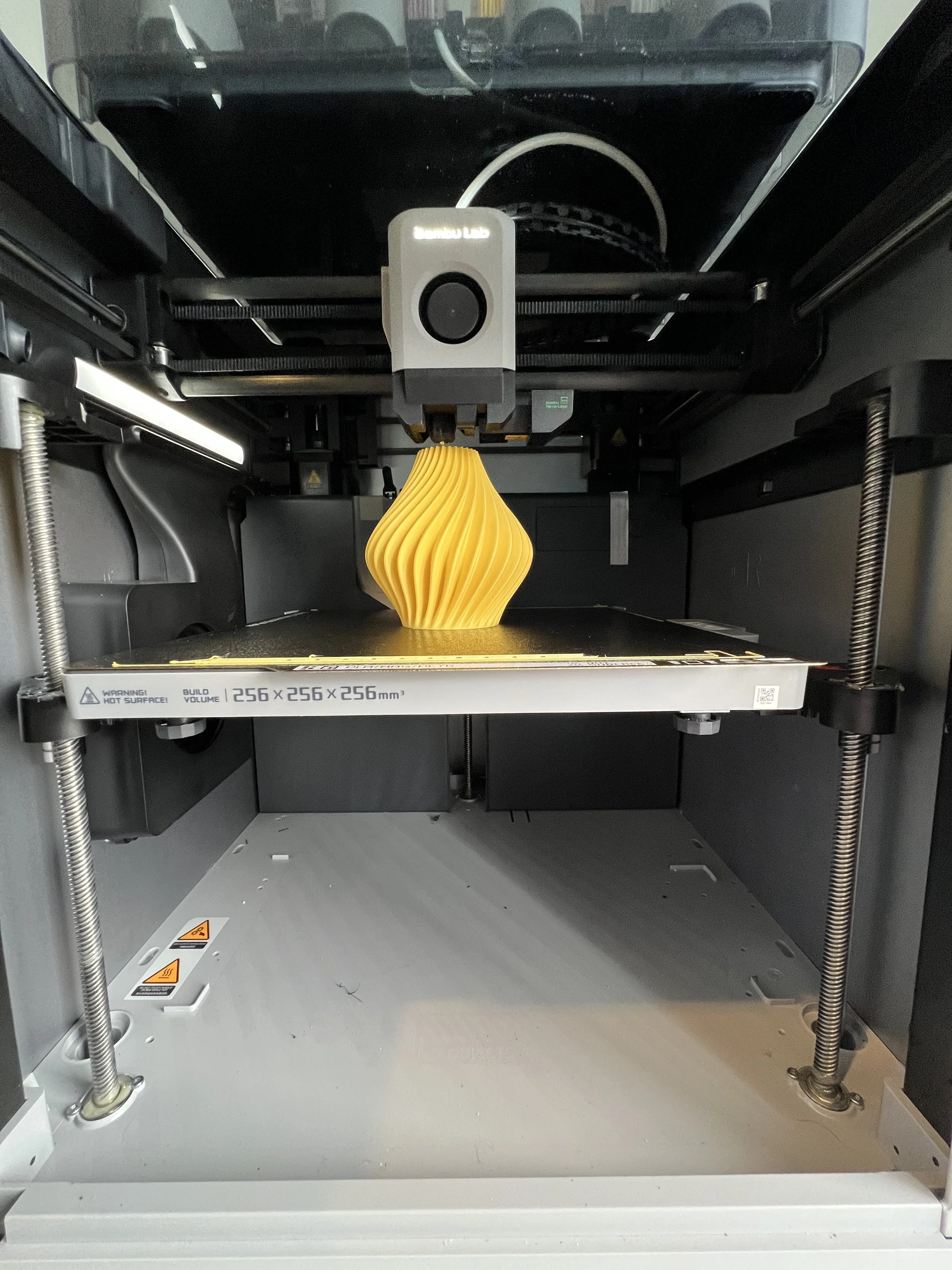 A 3D printer printing a yellow, spiral-shaped object.