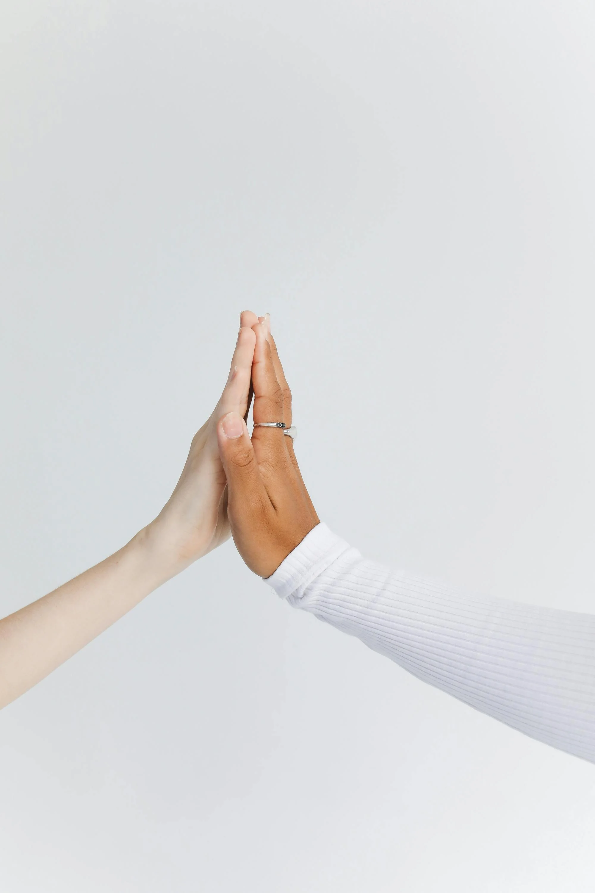 Two hands meeting in partnership against a neutral background