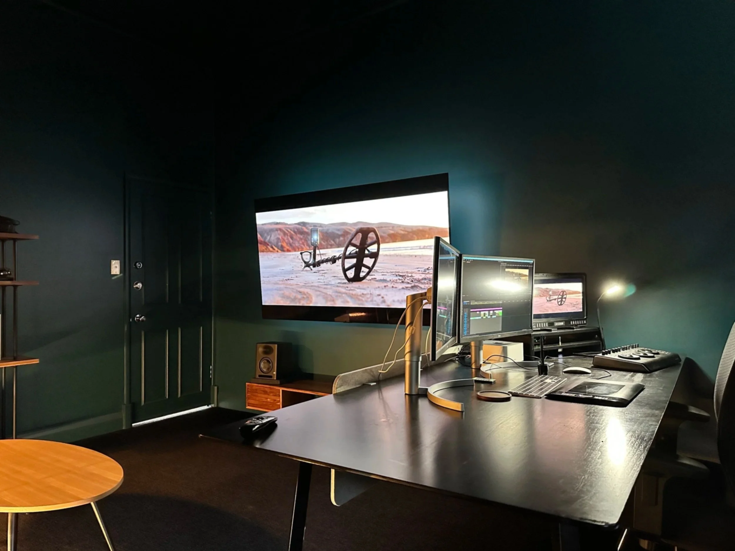 A dark and modern post-production suite complete with client monitor and high-end colour grading console.