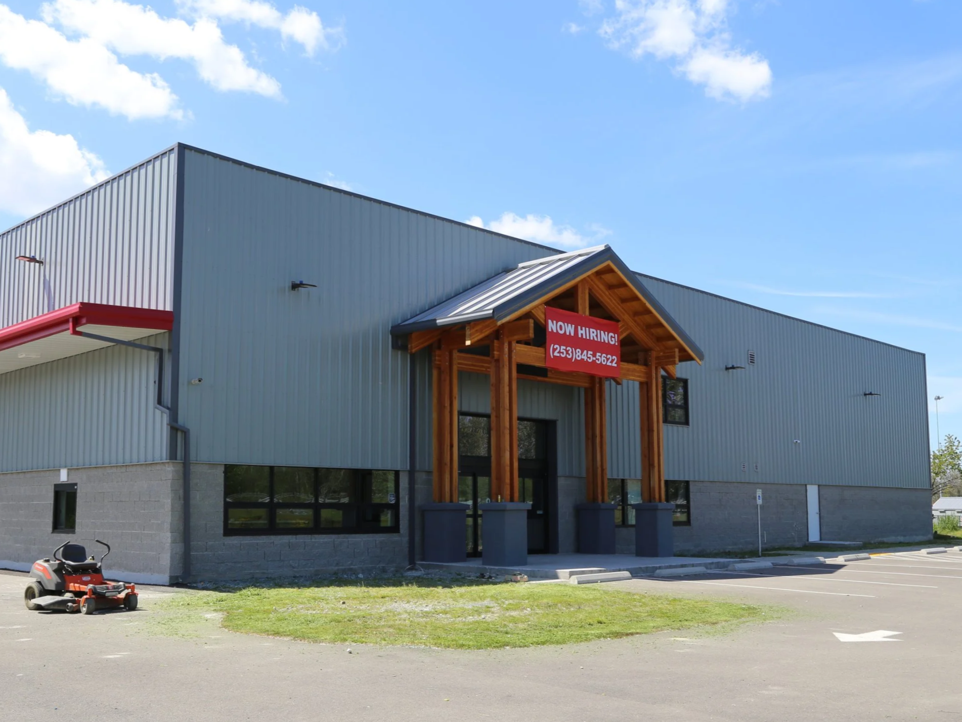 Commercial building with a red 'Now Hiring' sign and a phone number in a parking lot. Commercial construction of Puyallap Smoke Shop in Puyallap, Washington.