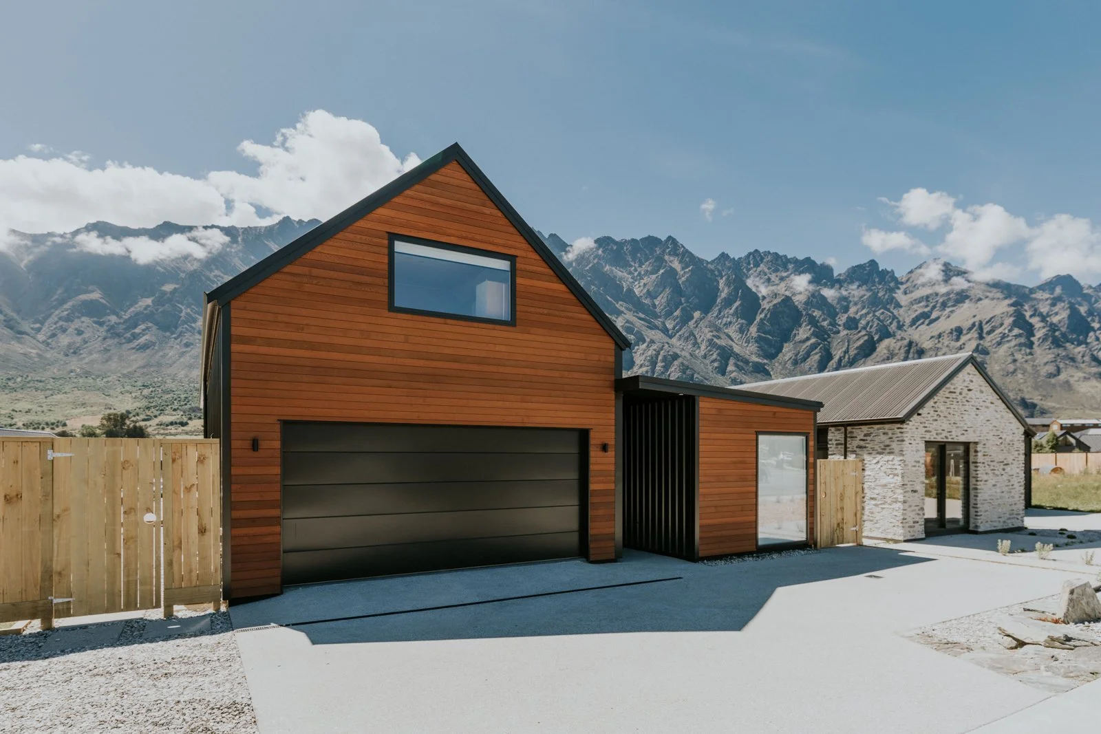 Modern house with wooden exterior, attached garage, and mountain backdrop.