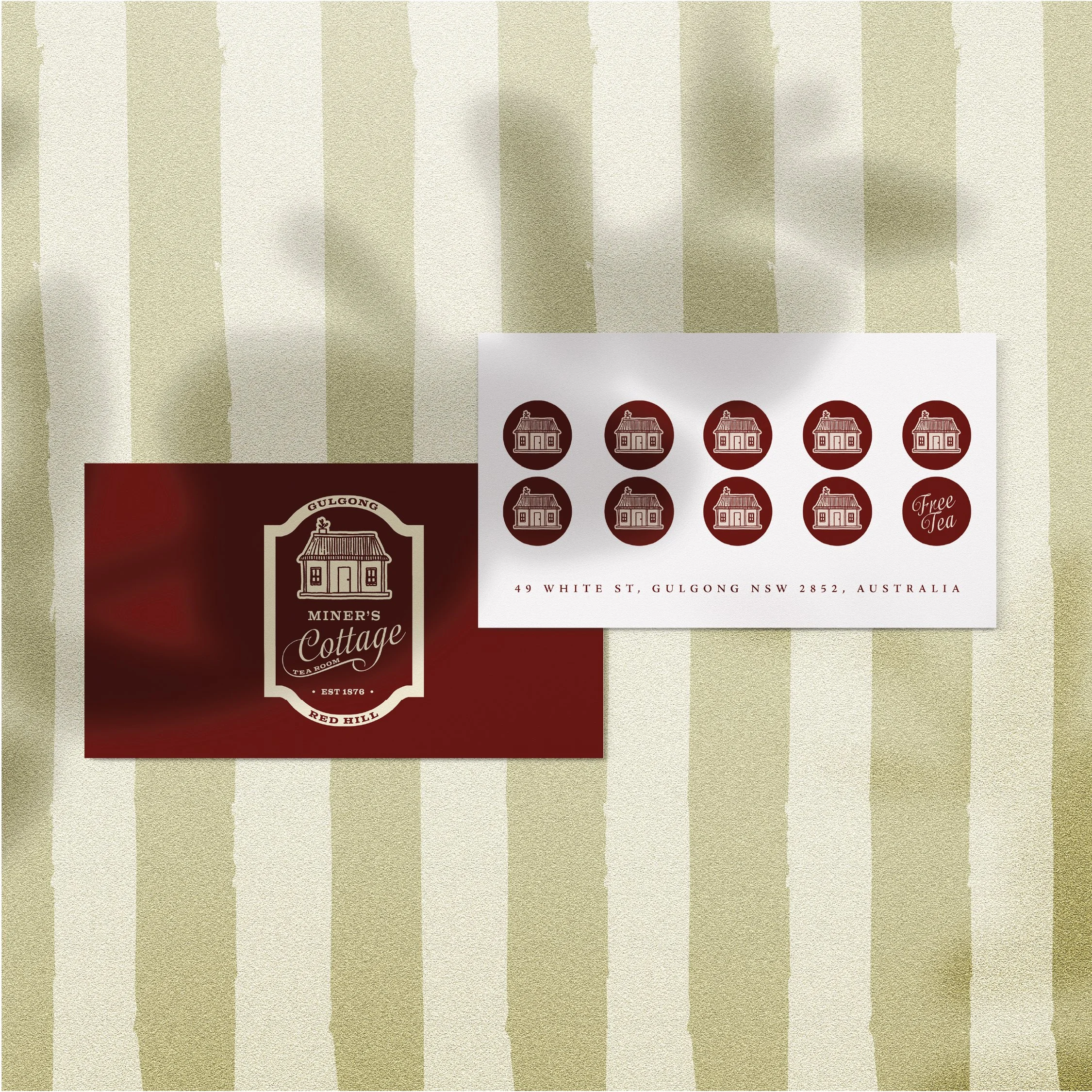 A business card for Miner's Cottage featuring a logo with a cottage illustration and text, and a sheet with circular stickers of the cottage logo and address, on a striped tablecloth.