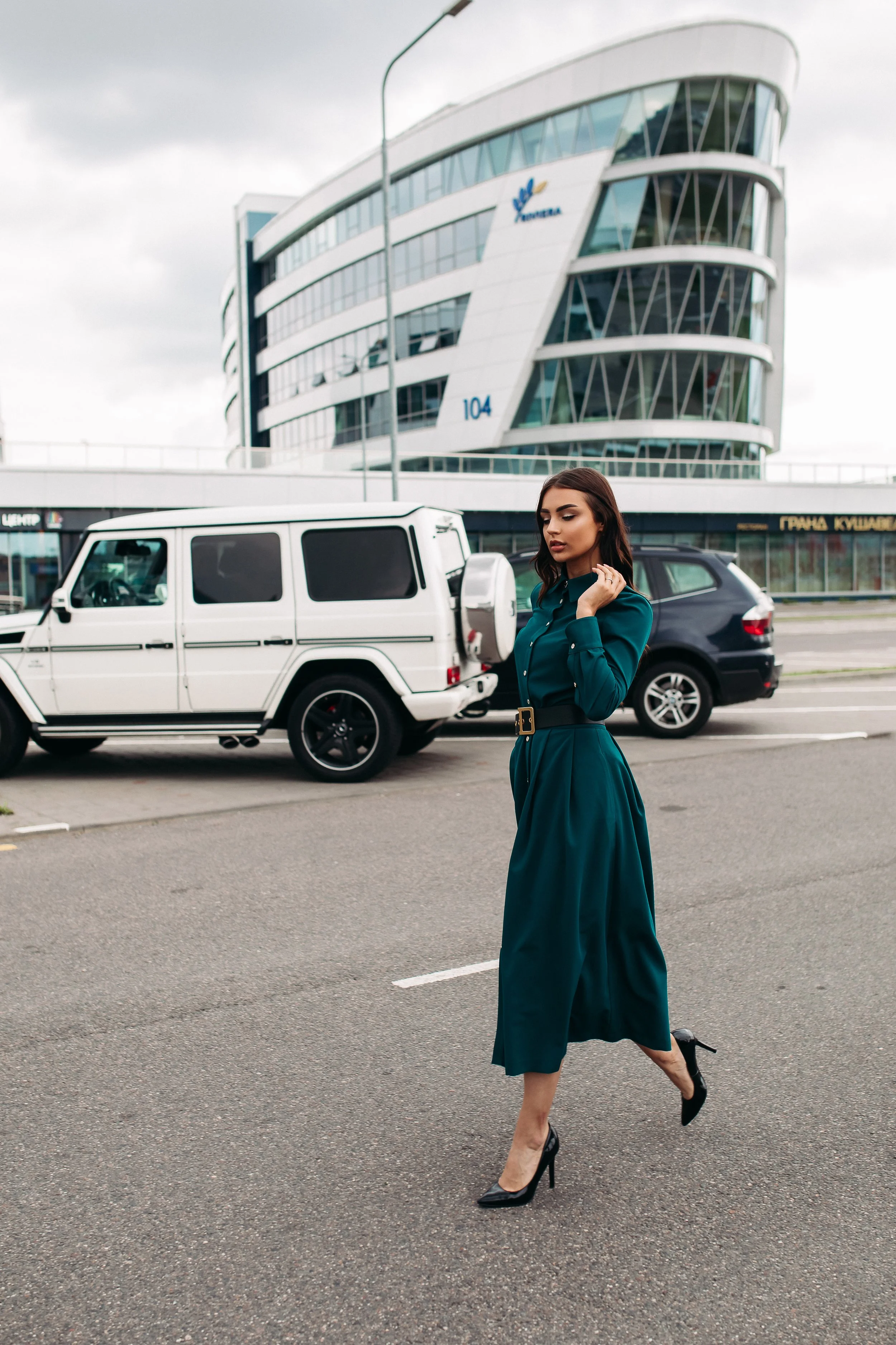 full-length-stock-photo-pretty-brunette-woman-long-emerald-green-dress-with-buttons-black-leather-heels-walking-confidently-along-street-against-modern-buildings-cars.jpg