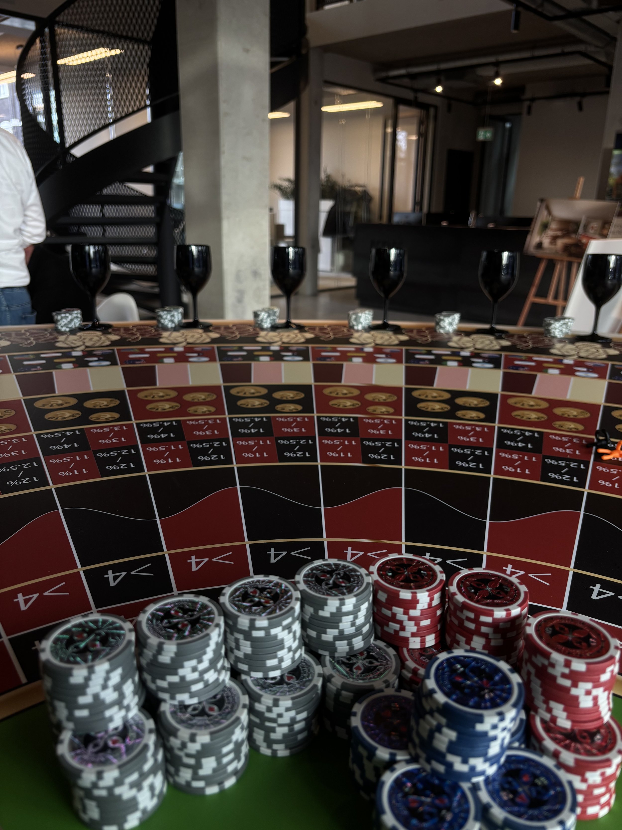 Gokken op een roulette tafel met kleurrijke fiches, zwarte glazen, en een casino omgeving.