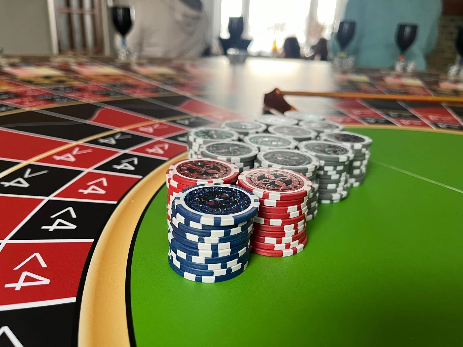 Rouler met casinogeld op een groene roulette tafel, met gestapelde fiches in het midden en de roulette in de achtergrond