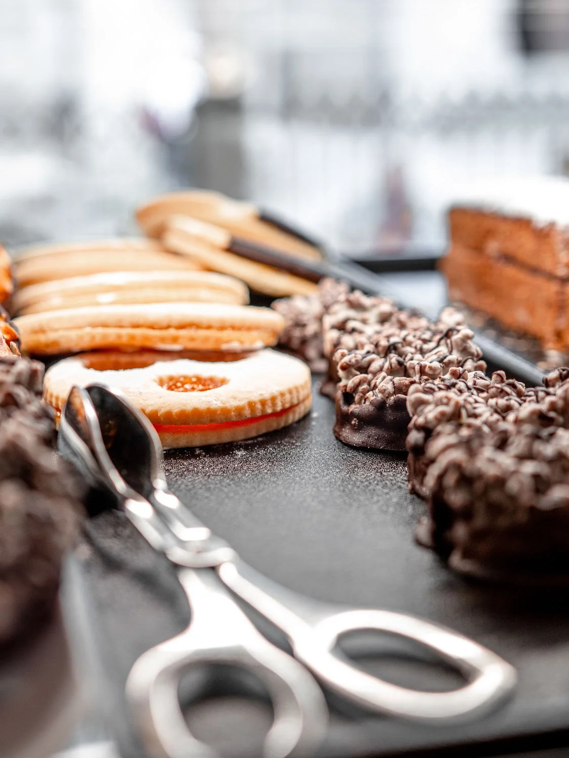 Verschiedene Süßigkeiten und Gebäck auf einer Theke, darunter Kekse, Schokoladenriegel und Kuchen.