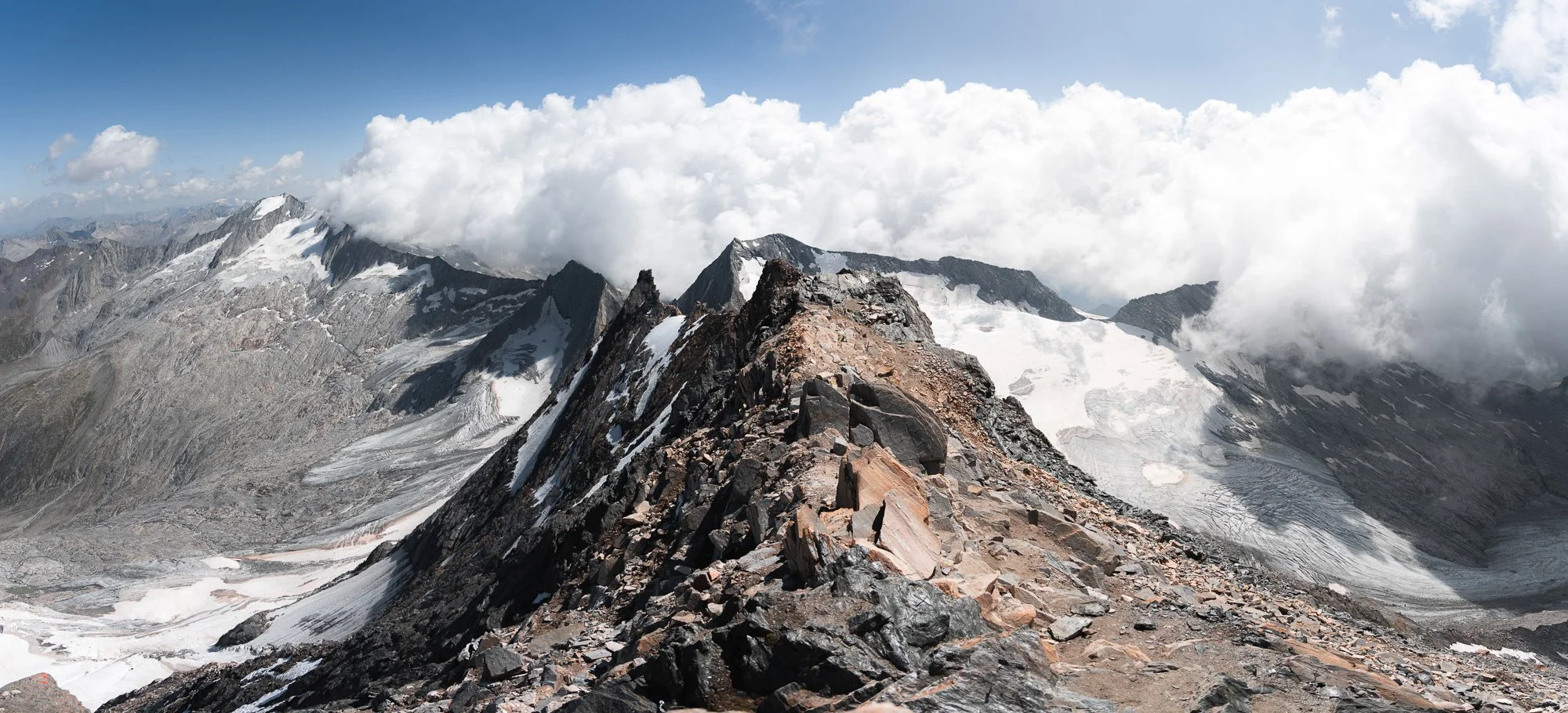 Bergketten und Gletscher in den Alpen mit Wolken im Himmel.