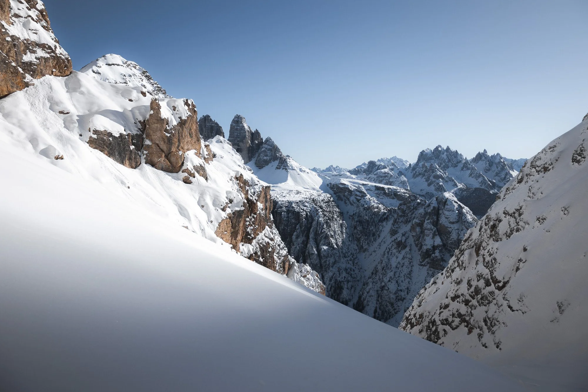 Berglandschaft mit schneebedeckten Gipfeln und tiefen Schluchten unter klarem blauen Himmel