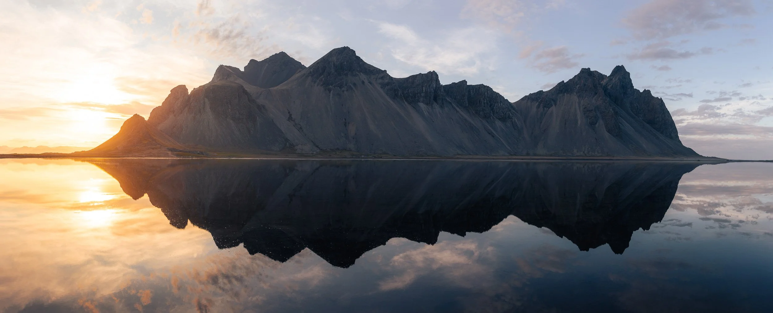 Berglandschaft bei Sonnenuntergang mit Reflexion im Wasser am Vestrahorn in Island.