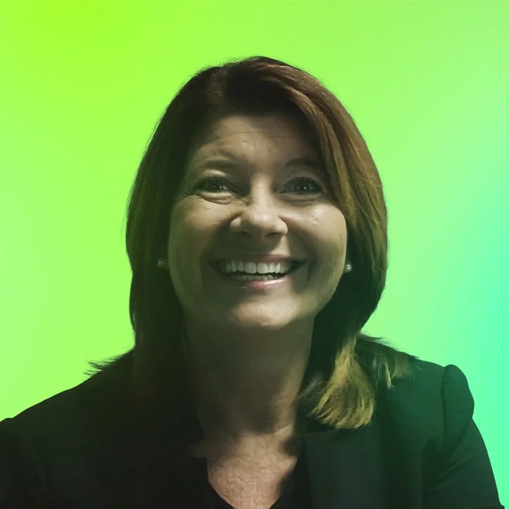 Eine lächelnde Frau mit braunen Haaren vor grünem Hintergrund.