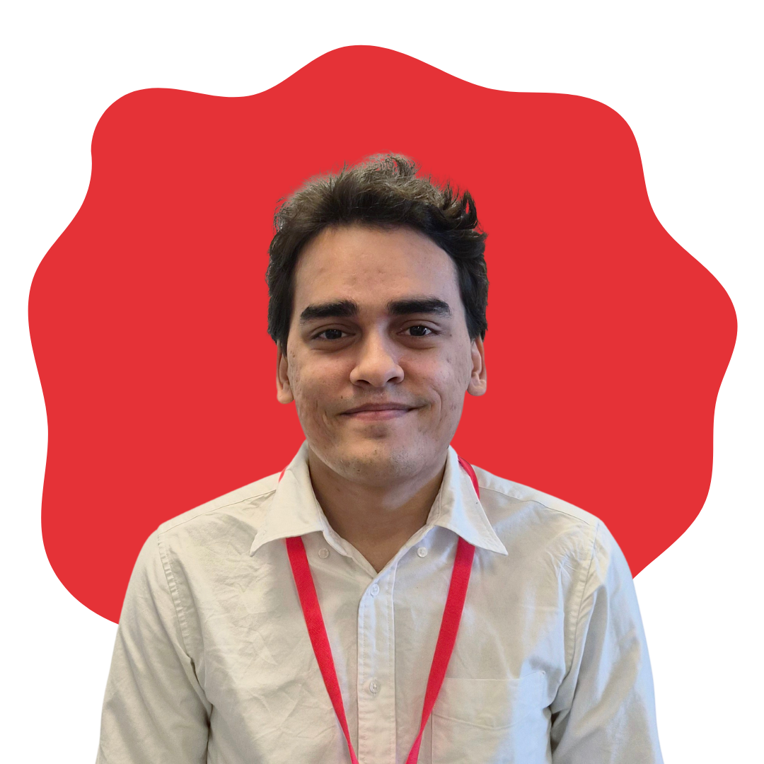 Young man with short dark hair wearing a beige shirt and red lanyard, smiling in front of a red shape on a white background.