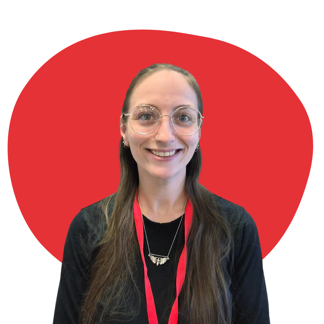 A woman with long brown hair, glasses, and a nose piercing, smiling in front of a red circle background.