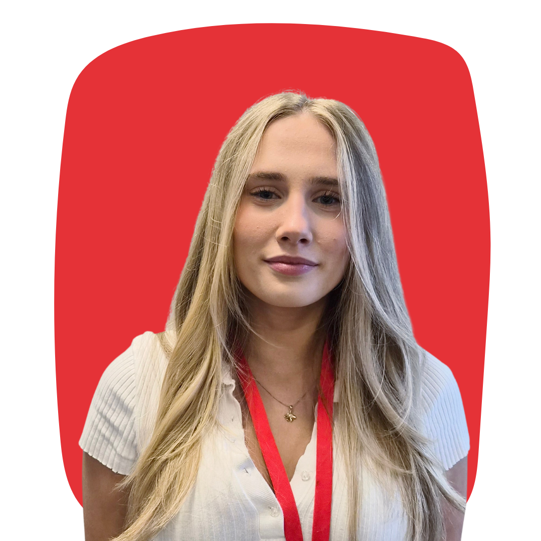 A young woman with long blonde hair wearing a white shirt and a red lanyard against a red background.