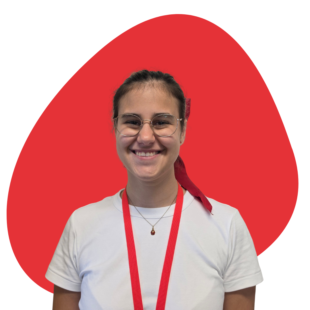 Young woman smiling, wearing glasses, a white t-shirt, a red lanyard, and a red bandanna tied in her hair, standing in front of a white background with a large red abstract shape behind her.