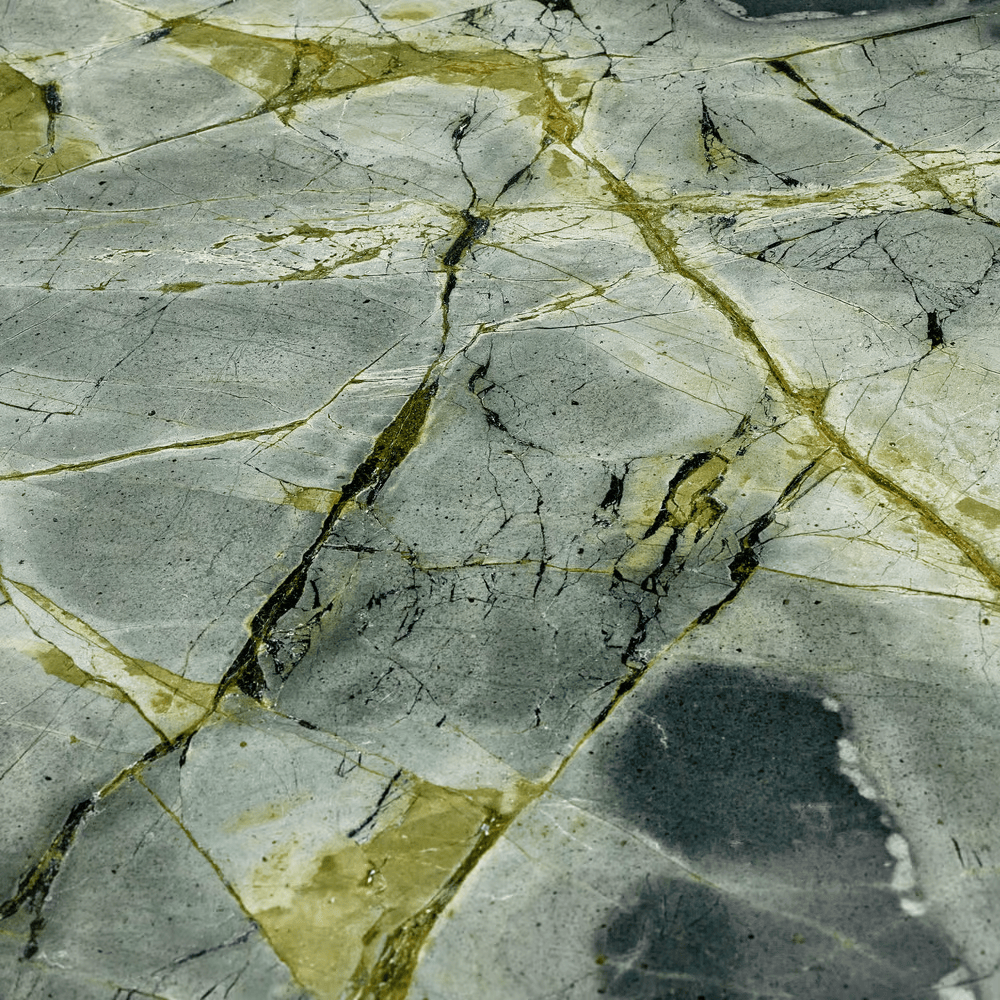 Close-up of a cracked marble surface with gray, yellow, and black veining.