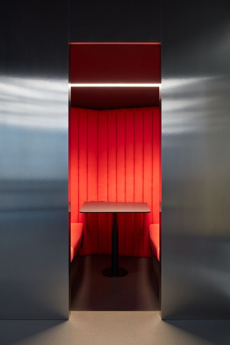 Cabine de silence avec des sièges en velours rouge et un petit tableau noir au centre.