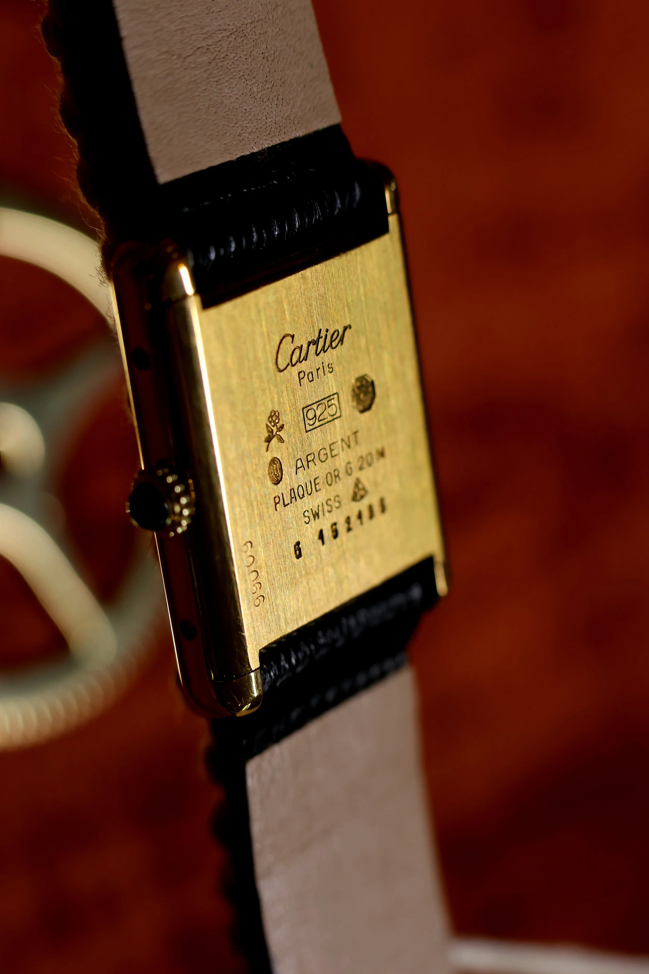 Montre Cartier plaquée or 20 microns et bracelet noir, affichant des inscriptions et des symboles liés à la marque.