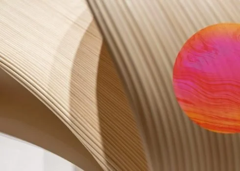 Une composition artistique de formes géométriques en bois avec un cercle orange et rose en relief.