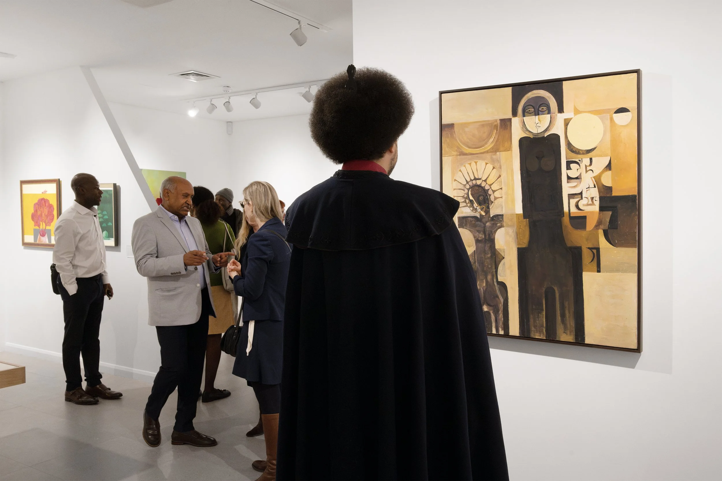 People viewing abstract artwork in an art gallery, including a person with a large afro in the foreground facing a large black and yellow painting.