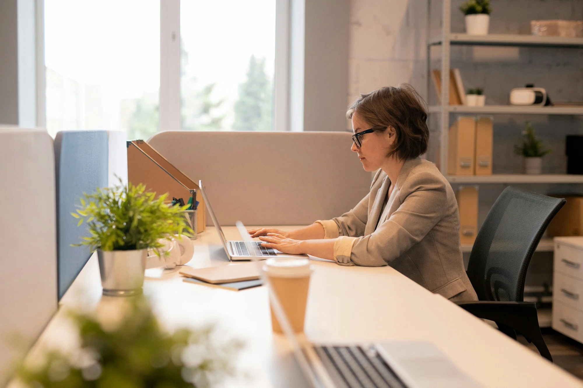 A woman sitting at a desk typing on her computer's keyboard