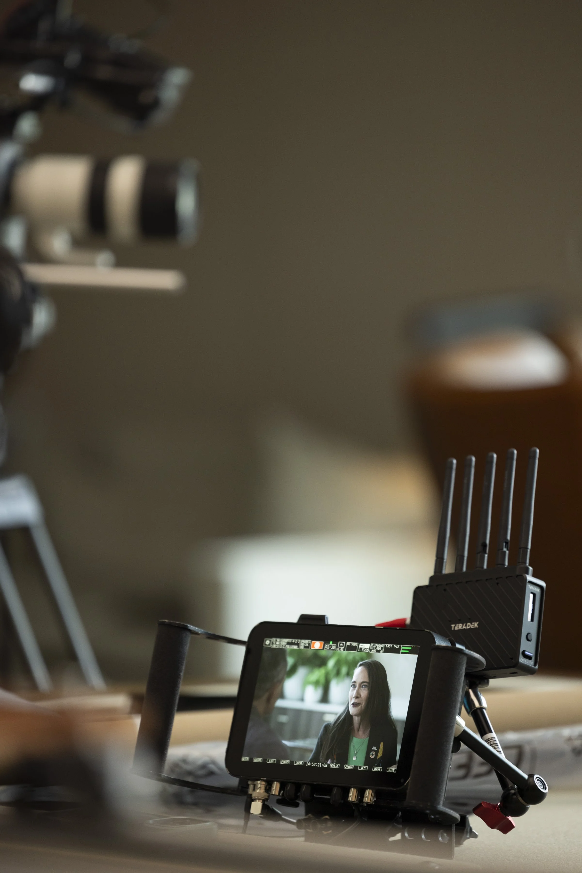 A camera and monitor setup filming a woman in an indoor environment for a video or interview.