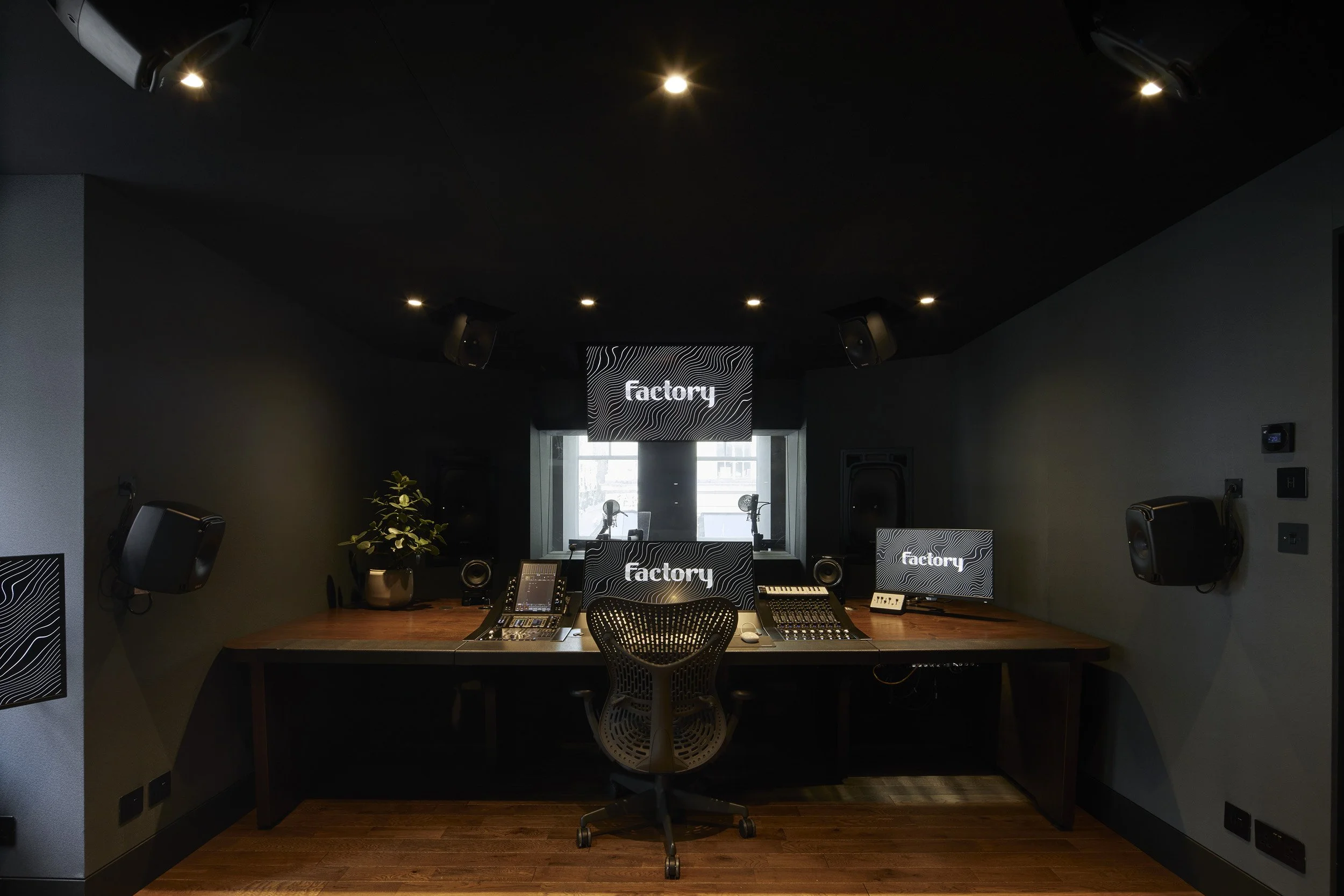 Control room with monitors and mixing console for spatial immersive audio production.